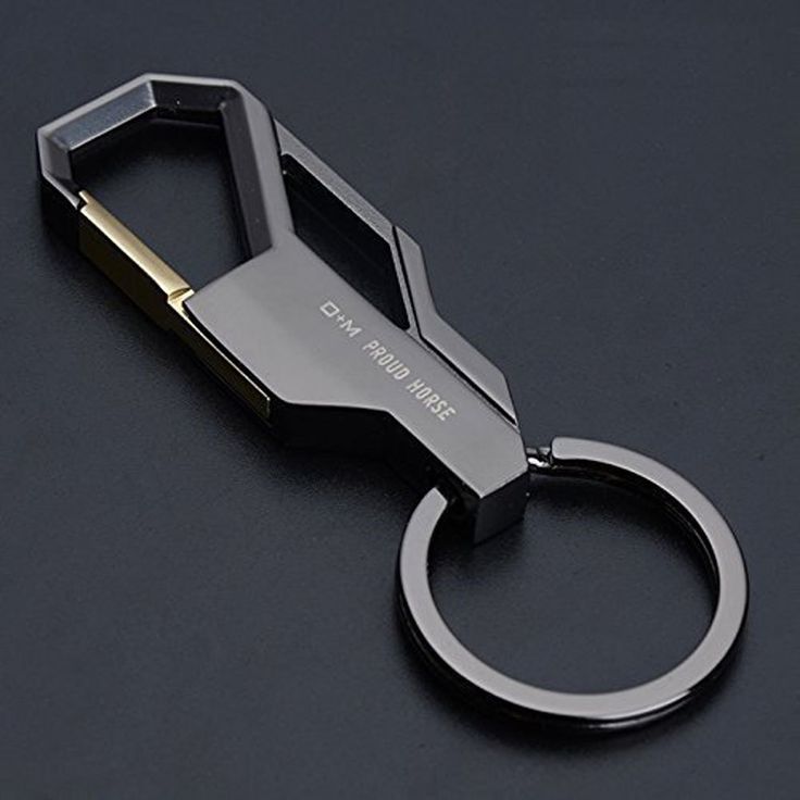 a metal keychain that is on top of a black surface with a gold ring