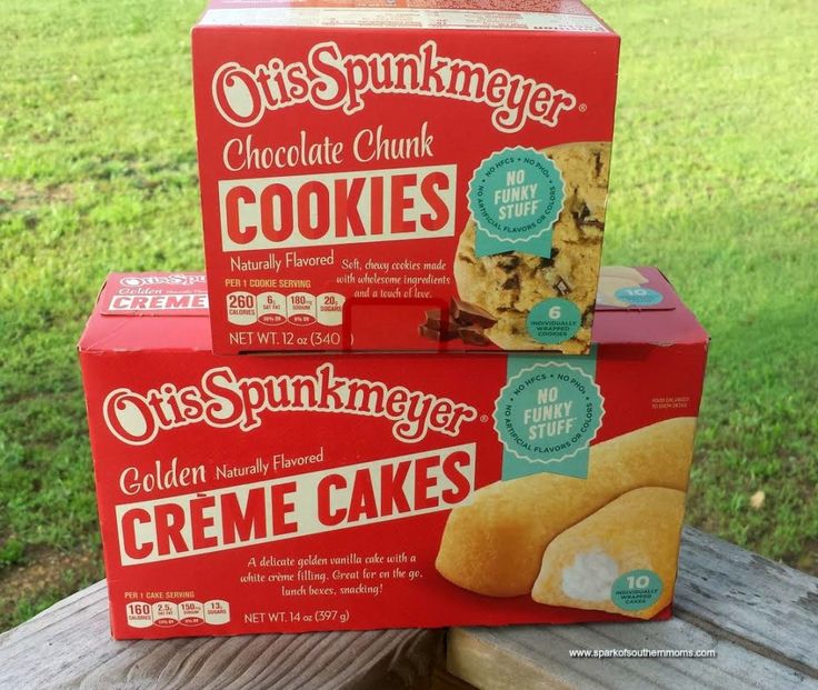 two boxes of cookies sitting on top of a wooden bench in front of some grass