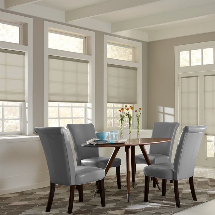 a dinning room table with four chairs and a bowl of flowers on the table