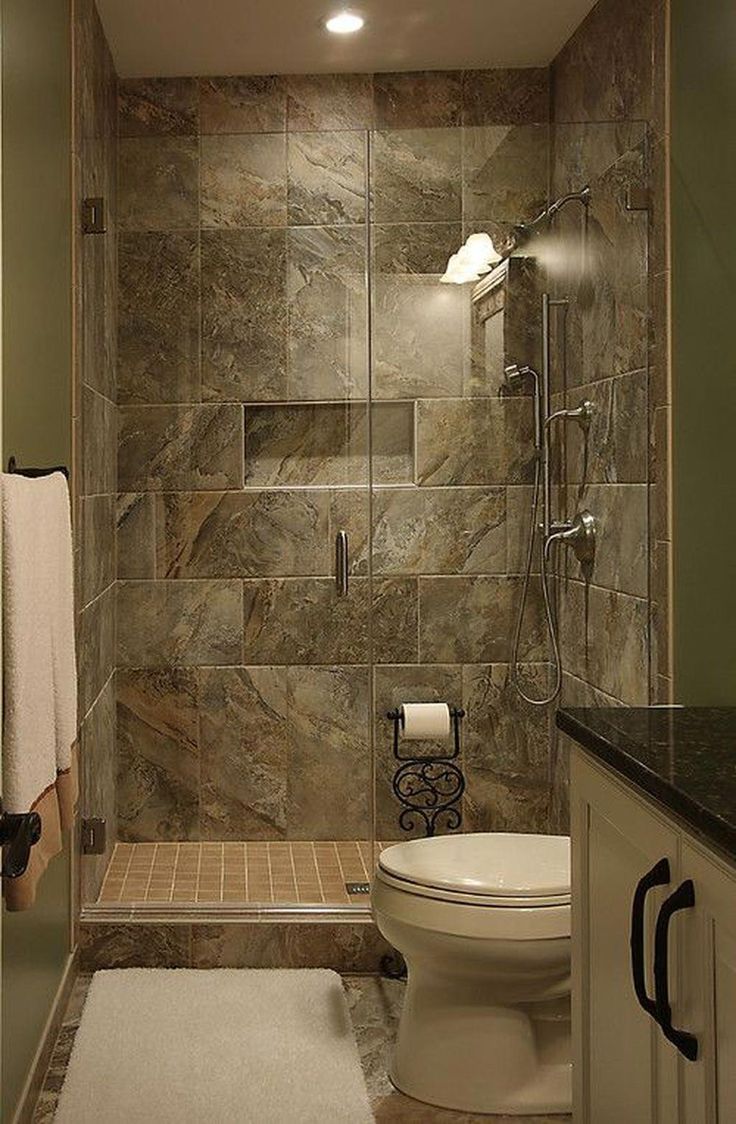 a walk in shower sitting next to a toilet under a bathroom light above a sink