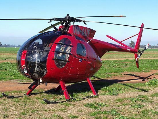 a red helicopter sitting on top of a grass covered field