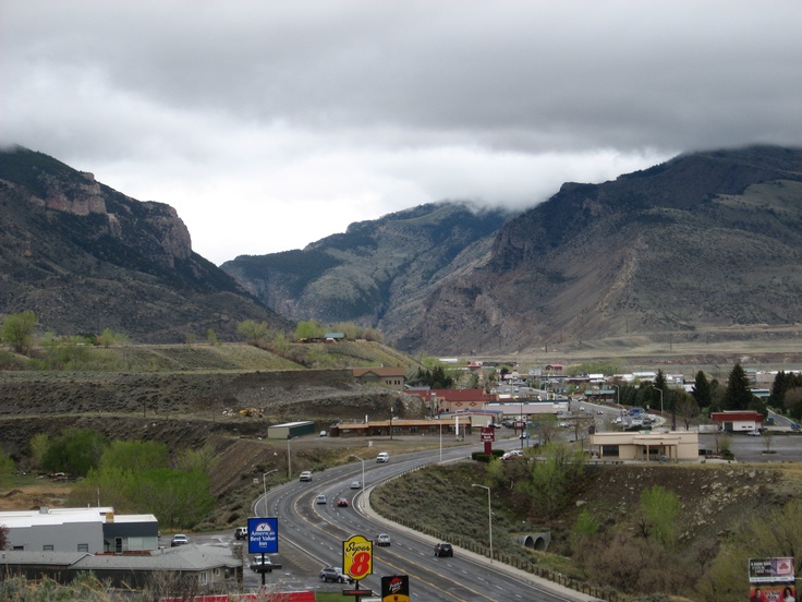 a highway with mountains in the background and cars driving down one side, on an overcast day