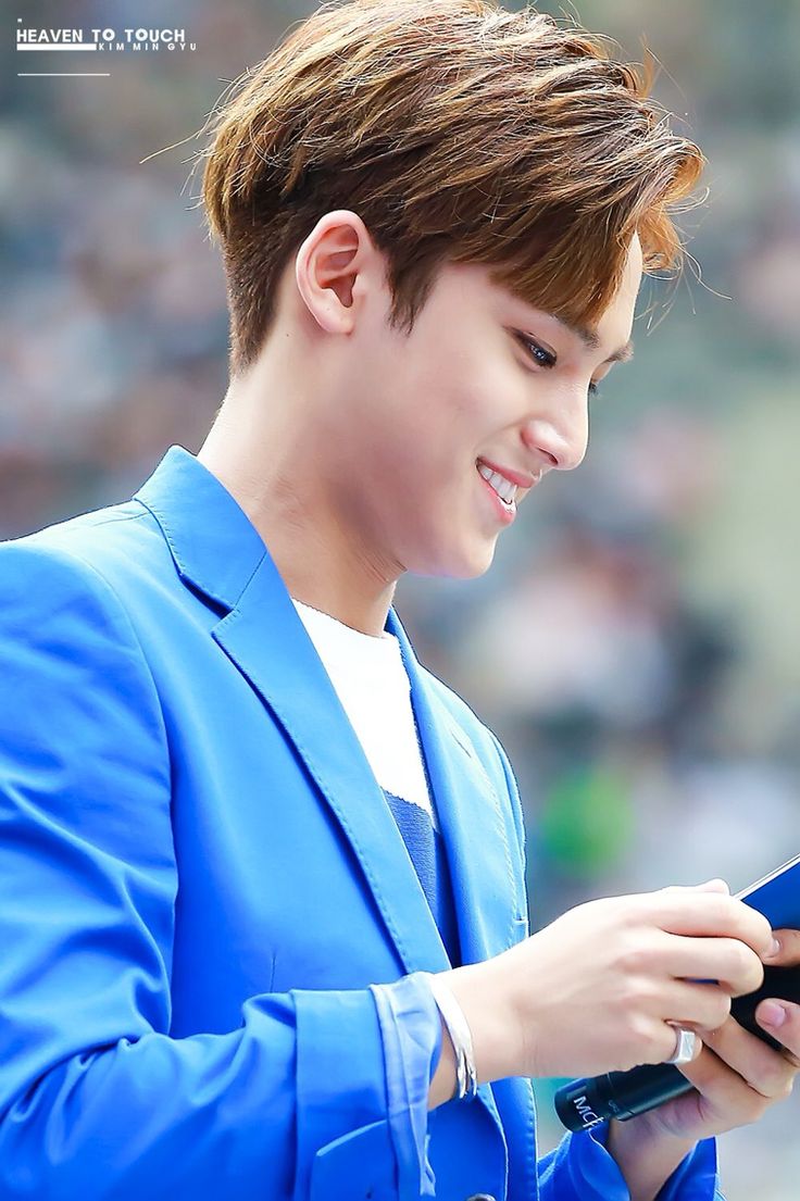 a young man in a blue suit looking at his cell phone