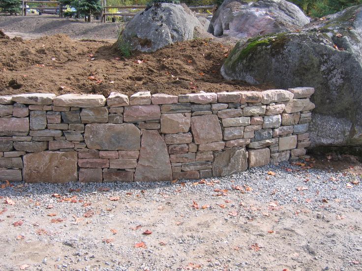 a stone wall in the middle of a dirt field