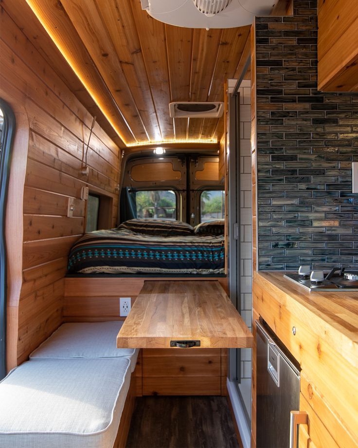 the interior of a camper with wood paneling and built - in kitchen area