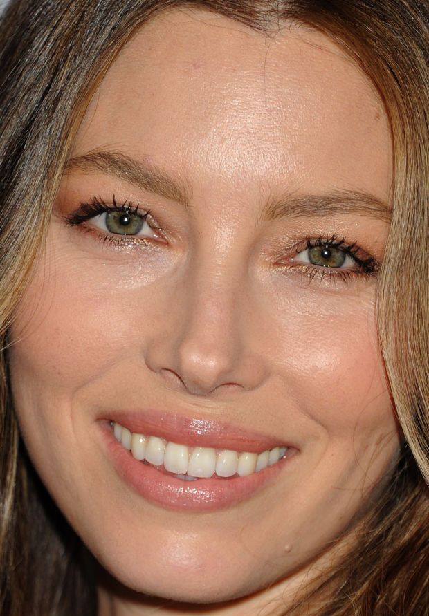 a close up of a woman smiling with brown hair and light green eyeshadow