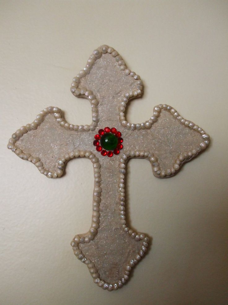 a white cross with a red and green bead on it's center piece