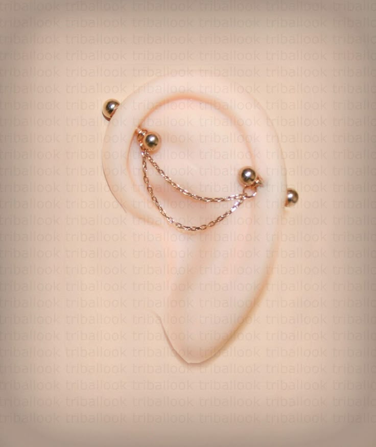 a pair of ear piercings with pearls and chains hanging from it's sides