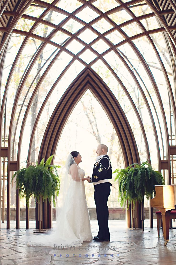 a bride and groom standing in front of an arch