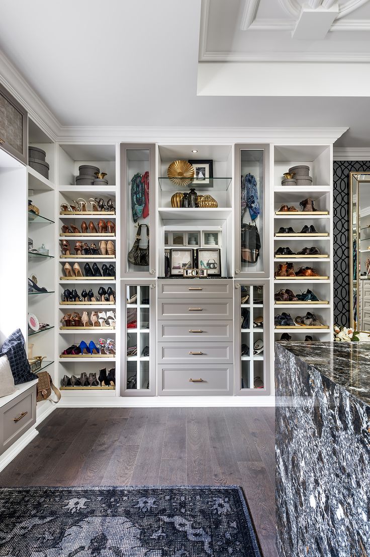 a large walk in closet with lots of shoes on the shelves and drawers next to it