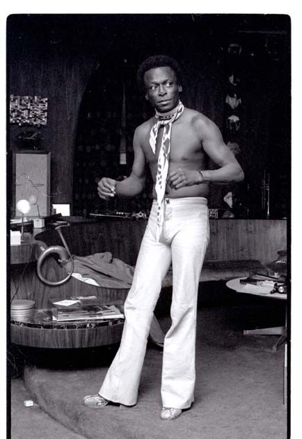 a man in white pants and tie standing next to a table