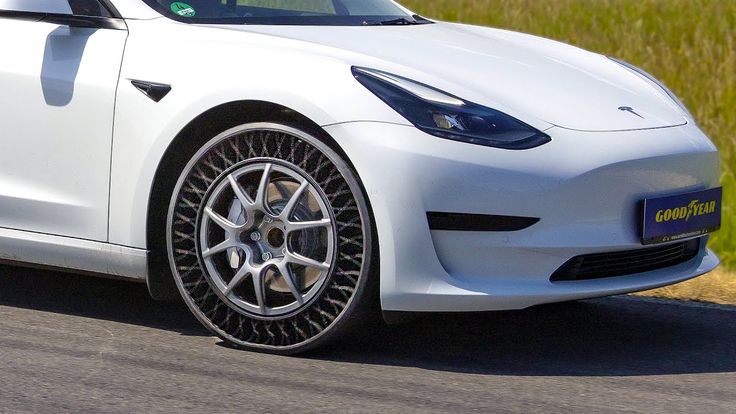 a white sports car driving down a road next to tall grass and trees in the background