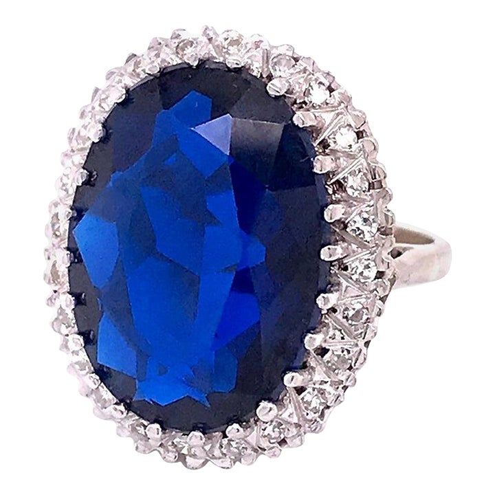 A very fine gold and multi-gemstone cocktail ring.  In 14k white gold.   Set with a large deep blue oval-cut topaz surrounded by a halo of 24 small round-cut diamonds.  Simply an eye-catching ring that is fun to wear and makes you look!  Marks: Marked to the shank 14k for gold fineness.  Dimensions: Length: ca. 22mm Width: ca. 20mm  Ring Size: ca. 6 3/4  Gemstone Dimensions: Topaz: ca. 18mm x 13mm x 5.5mm  Items purchased from this dealer must delight you. Topaz Cocktail Ring, Golden Rings, White Gold Set, Gold Cocktail Ring, Golden Ring, Gold Cocktail, Diamond Cocktail Rings, Large Jewelry, Gems Jewelry