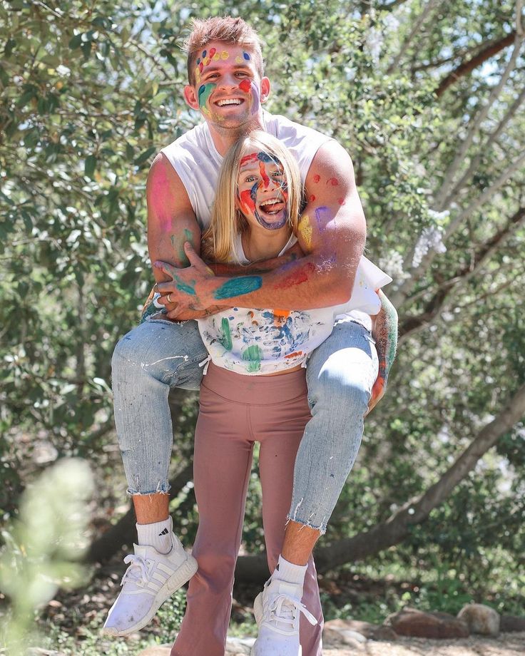 a man and woman with face paint on their faces posing for the camera in front of some trees