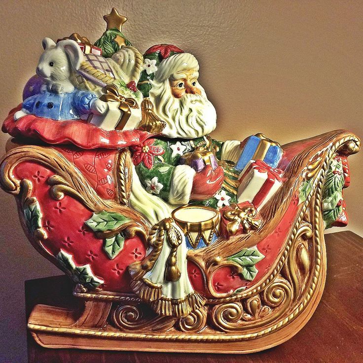 a christmas sleigh with santa claus and other figurines in it on a table