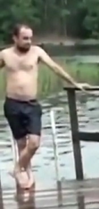 a shirtless man walking across a bridge in the water with his arms outstretched and feet crossed