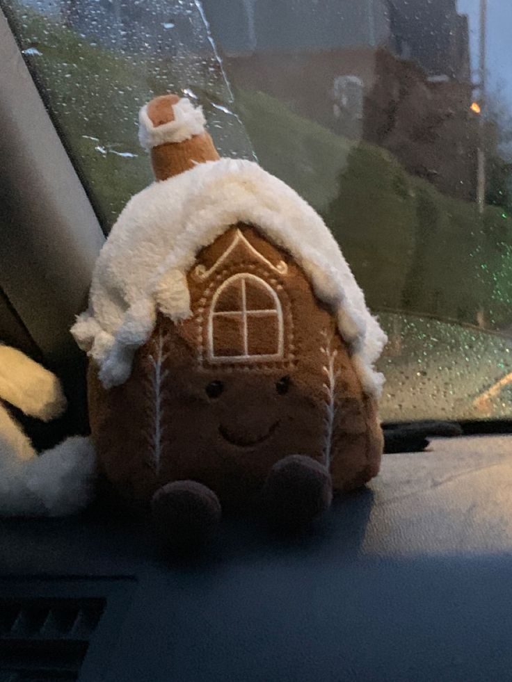 a gingerbread house is sitting in the front seat of a car with snow on it