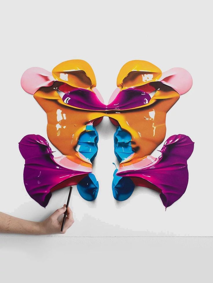 a person holding a paintbrush in front of a cut out butterfly