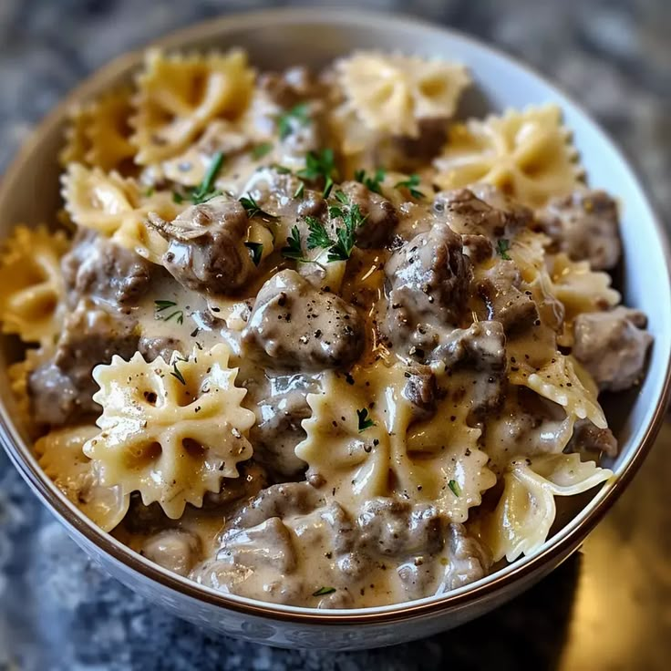 a bowl full of pasta with meat and gravy on it sitting on a table