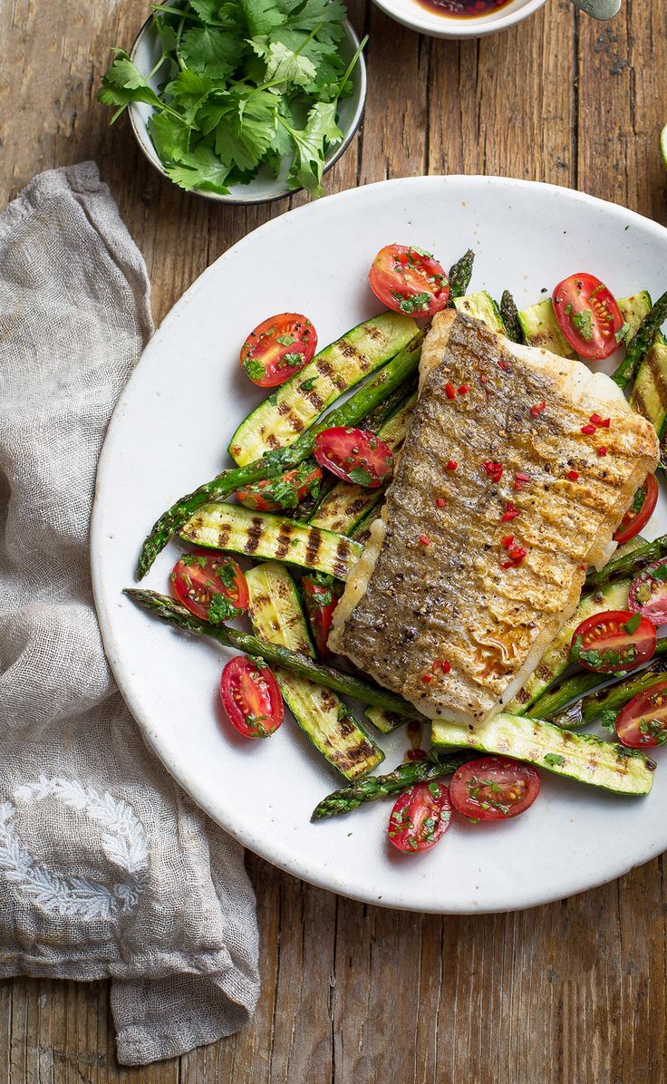 a white plate topped with grilled fish and veggies