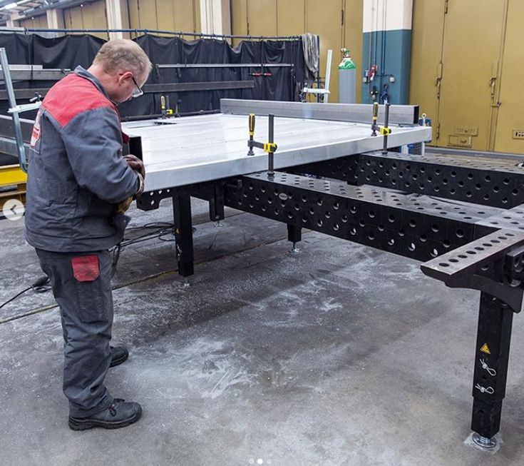 a man standing in front of a metal table with holes on the top and legs