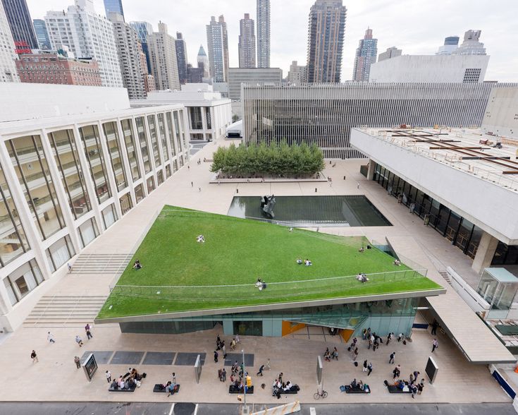 an aerial view of a green roof with people walking and sitting on the ground in front of it