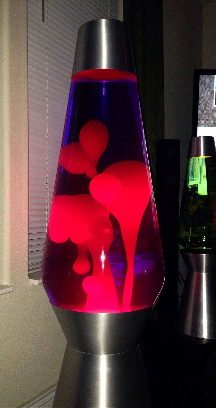 a glass vase with red liquid in it on a table next to two colorful vases