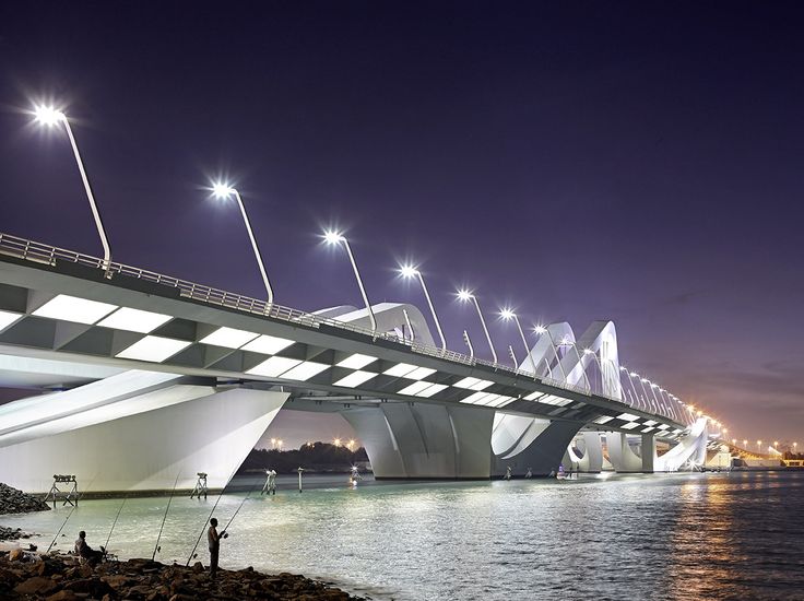 people fishing in the water under a bridge at night with lights shining on it's sides