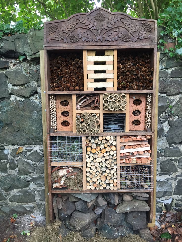 a bird house made out of wood and other items on display in front of a stone wall