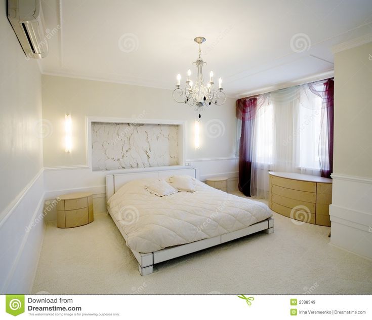 a bedroom with a bed, chandelier and two nightstands in the corner