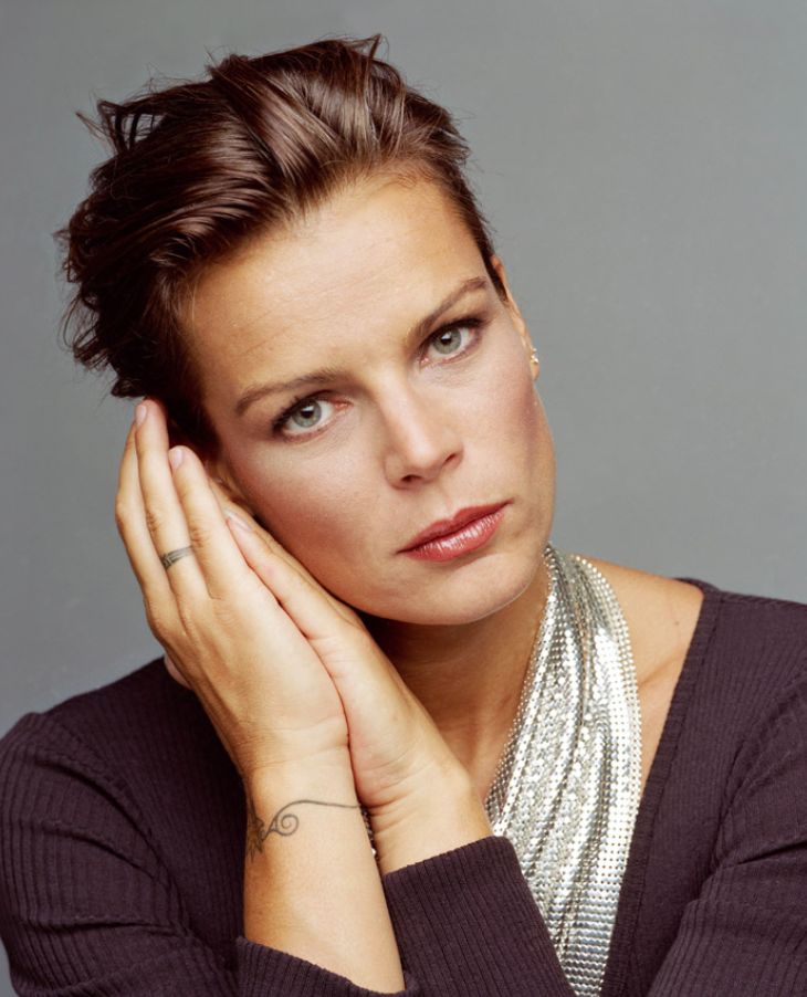 a woman with her hand on her chin and looking at the camera while wearing a necklace