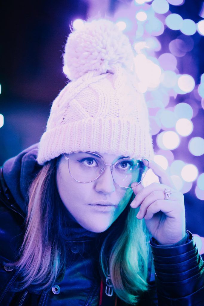 a woman wearing glasses and a white knitted hat is talking on her cell phone