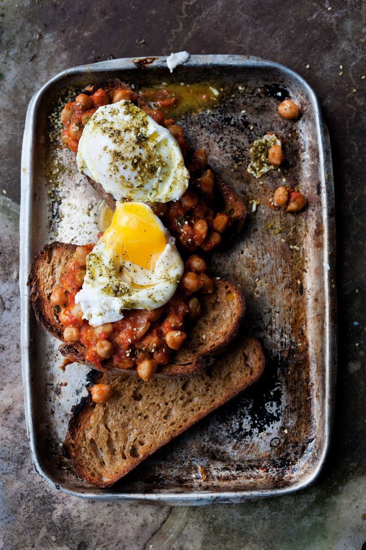 two eggs are sitting on top of toast in a pan, with beans and spices