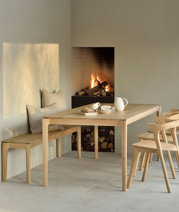 a dining room table and chairs with a fire place in the background