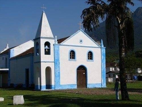 a white and blue church with trees in the foreground