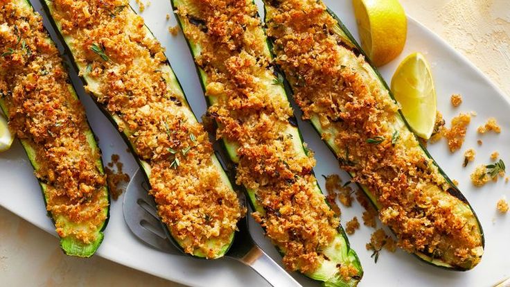 zucchini stuffed with bread crumbs and lemon wedges on a white plate