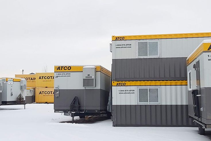 a row of yellow and gray containers sitting on top of snow covered ground