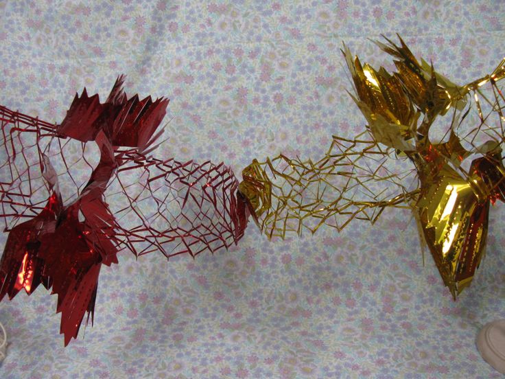 two vases filled with red and gold flowers on a tablecloth covered table cloth