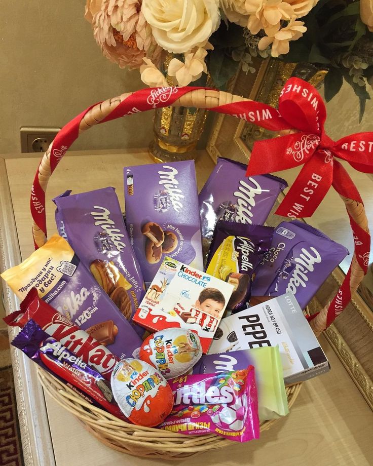 a basket filled with assorted candy and candies on a table next to flowers