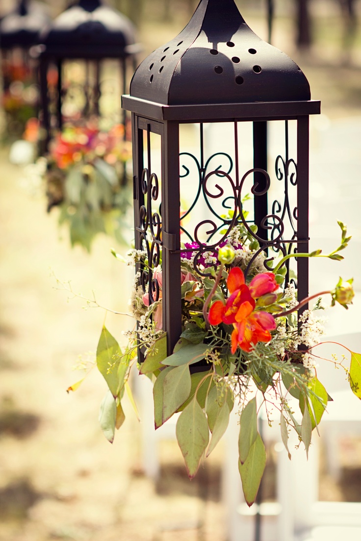 a lantern with flowers hanging from it's sides