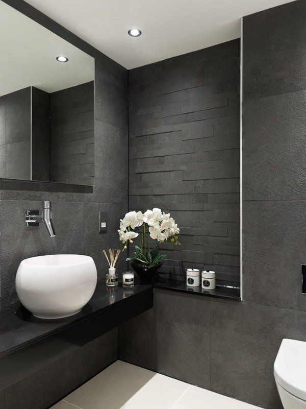 a bathroom with gray walls and white flowers in a vase next to the sink on the counter