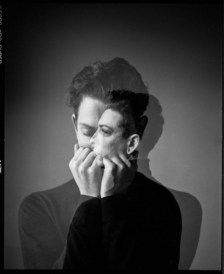 a black and white photo of a man with his hands on his face