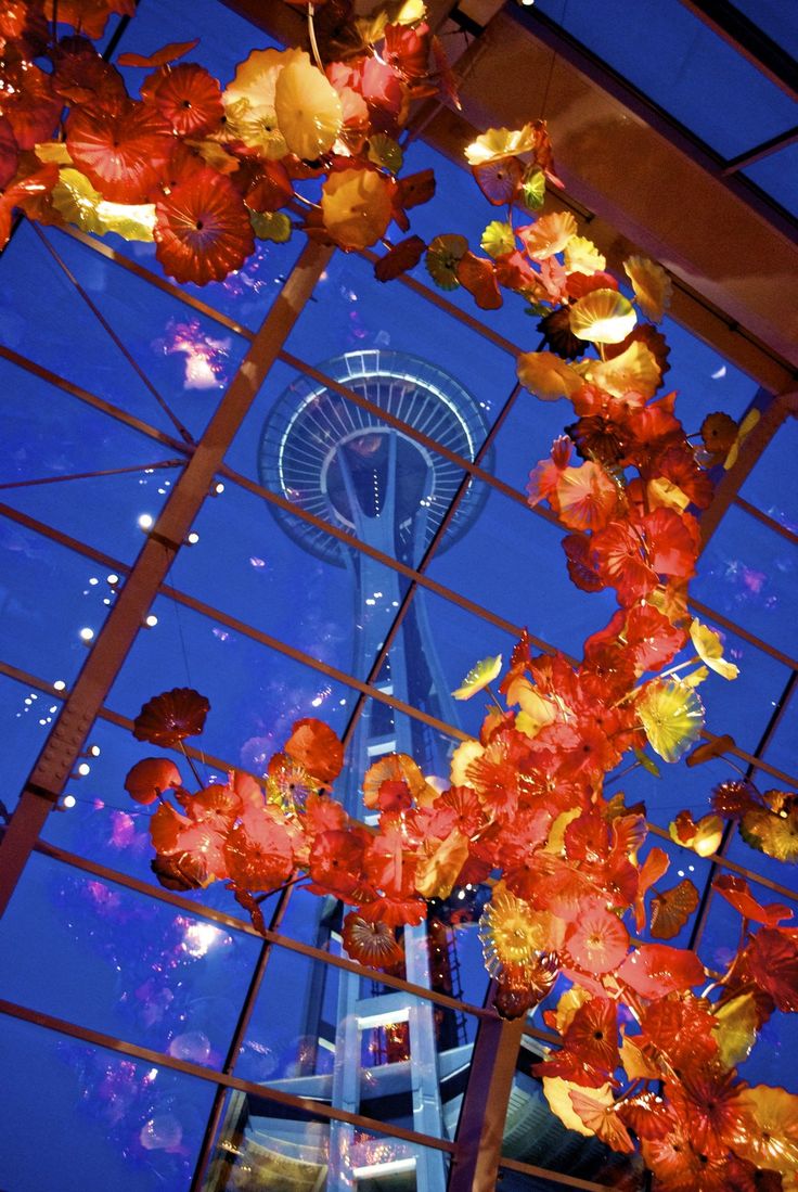 the sky tower is lit up at night with red and yellow flowers hanging from it's ceiling