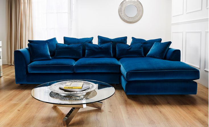 a living room filled with blue couches and a round glass coffee table on top of a hard wood floor