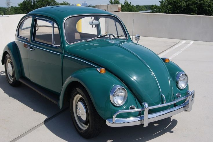 an old green beetle parked in a parking lot