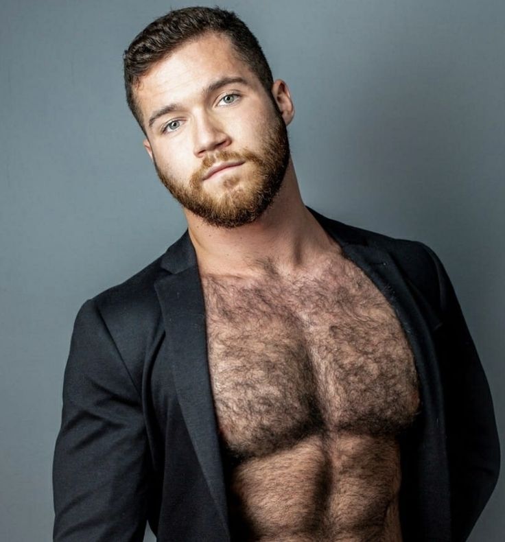 a shirtless man in a black suit posing for a photo with no shirt on