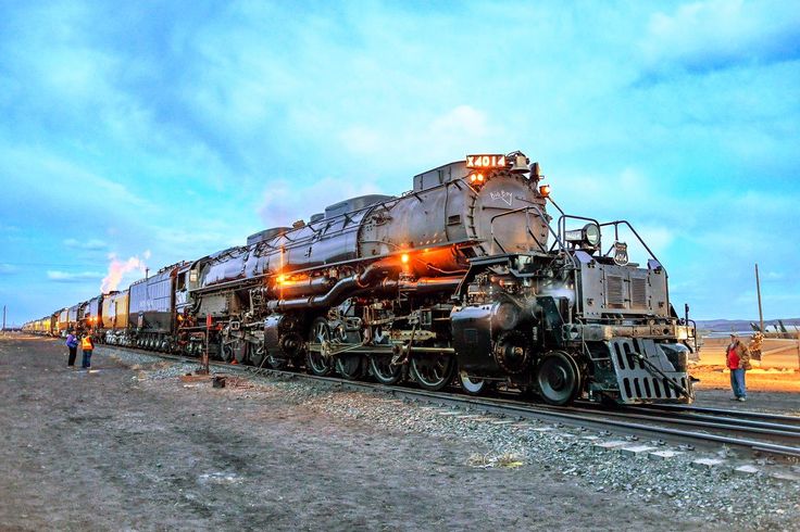 an old train is sitting on the tracks with people standing around and looking at it