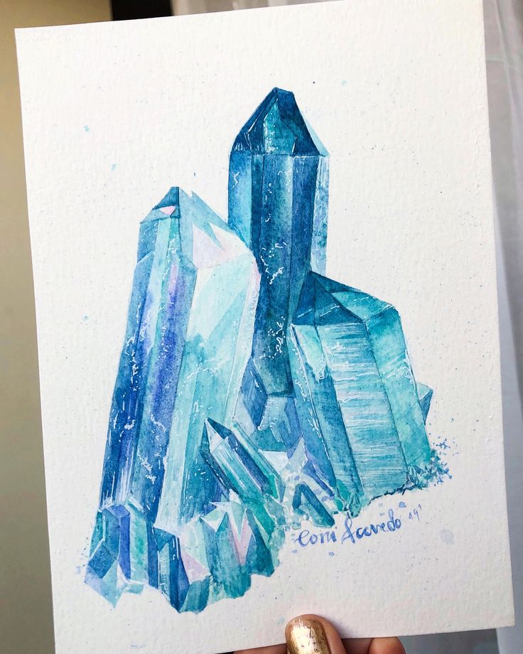 a person holding up a piece of art that has some blue crystals on top of it