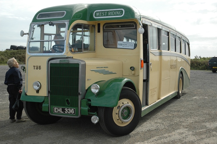 an old green and yellow bus parked in a parking lot with people standing around it