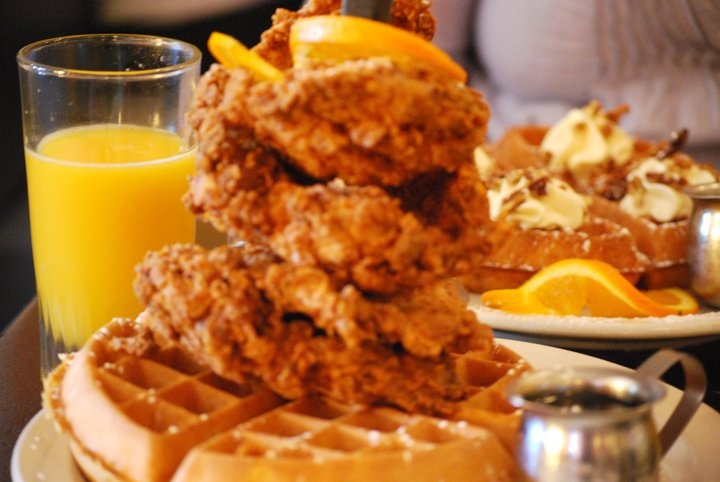 a stack of chicken and waffles next to orange juice